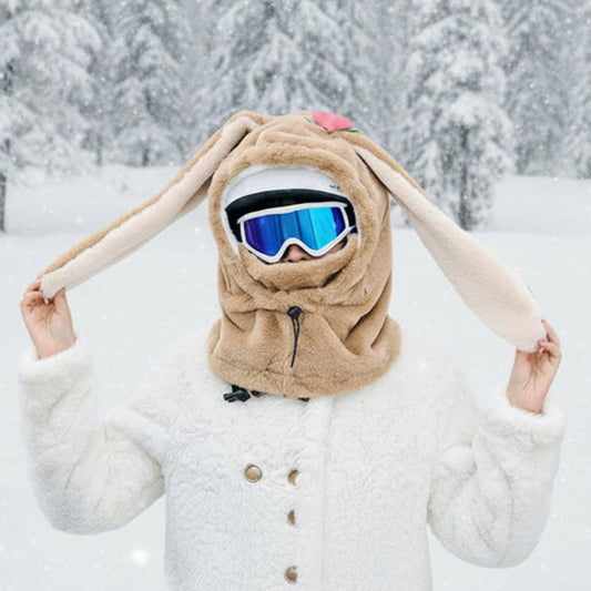 Person wearing a bunny hood with long ears and goggles, outdoors.
